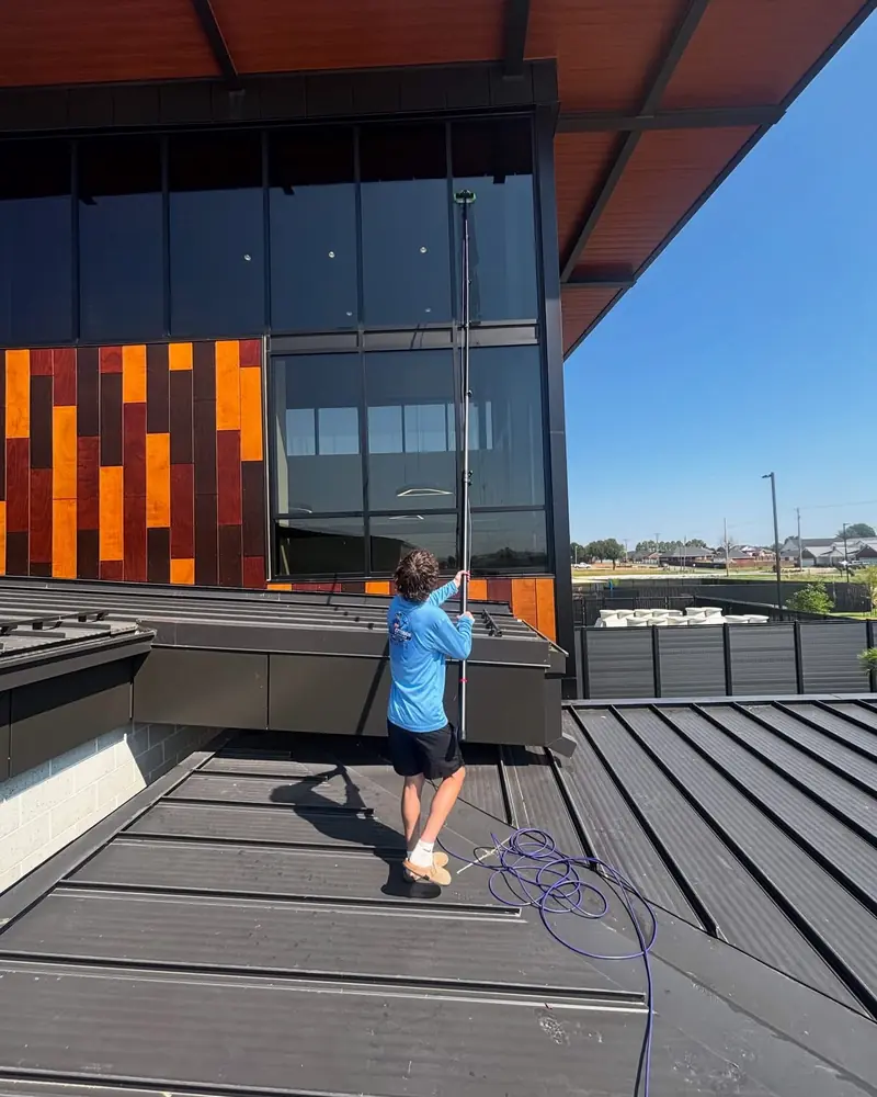 JB crew member cleaning high commercial glass with a water-fed pole